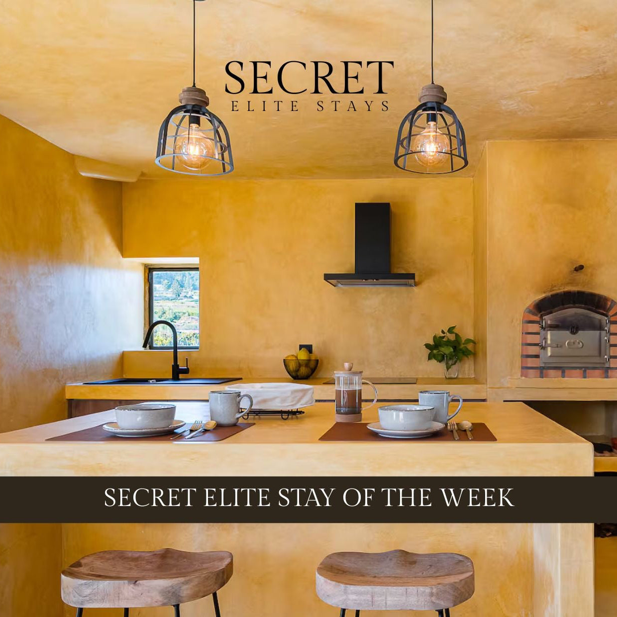 Modern kitchen with yellow walls and wooden table, featuring 'Secret Elite Stays' branding.